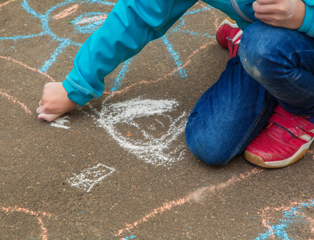 Little girl hand painting on the pavement outside, using colorful chalkの写真素材