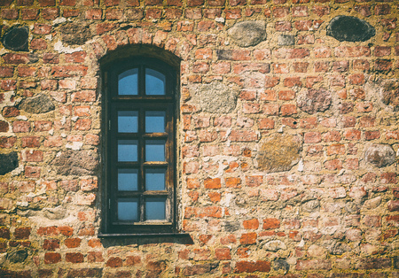 outdated medieval window in horizontal composition with old wall stoneの写真素材