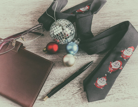 Business Christmas office on workplace with a tie, pen, glasses and Christmas decorations. Business and holiday concept, retro styleの写真素材