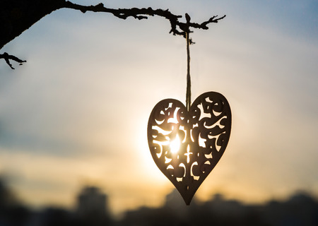 romantic heart hanged on a snowy forest shrub, sunset, winter, Valentine's Day, card