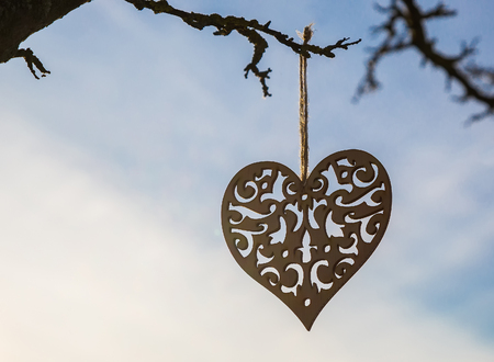 romantic heart hanged on a snowy forest shrub, winter, Valentine's Day cardの写真素材