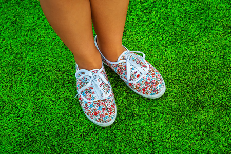 Feet in sneakers for walking outdoors. Conceptual image of a foot in shoes on green grass. Healthy lifestyle of a sporty woman, top viewの写真素材