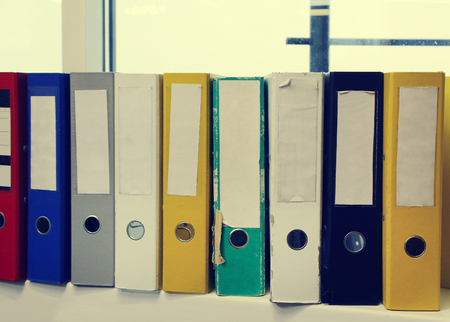 Dirty colored office folders for papers on a bookshelf, close-upの写真素材