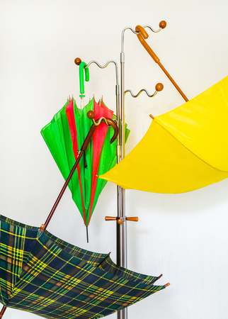 Office hanger with beautiful colored umbrellas on a white background. Concept of rain.の写真素材