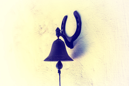 The Hanging Bell. An old rusty bell on a stone wall. the bell is used to make a call inside the...