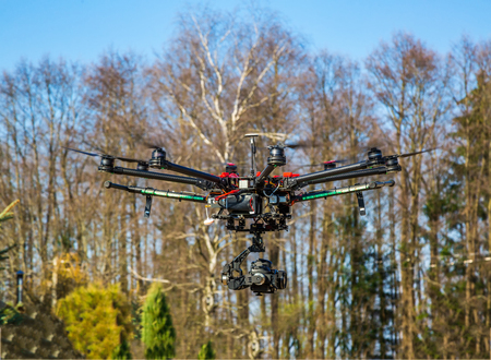 quadrocopter with camera flying over beautiful scenery and blue sky controlled by wireless remote control, digital hum, aeronauticsの写真素材