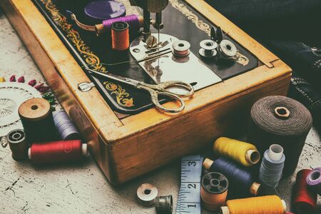 Sewing machine and accessories for sewing, scissors, needles and tailor meter on the table. The...