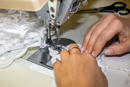 Women's hands sew, a sewing product on a professional production machine at a seamstress workplace....