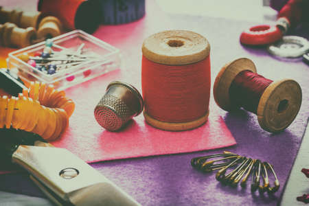 Creative image. A set of sewing accessories for sewing, spools of thread, fabrics, scissors and thimble close-up. Retro styleの写真素材
