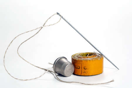 Old sewing accessories for sewing handmade on a white background, a tailor's tape, a needle and...