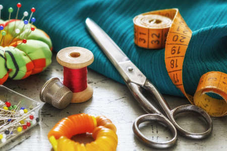 Retro sewing items. Various accessories for needlework. A set of sewing accessories for sewing, spools of thread, fabrics, scissors and thimble close-up. Retro styleの写真素材