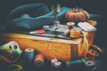 Old sewing machine and accessories for sewing, scissors, needles and tailor tape on the table. Retro sewing items. The concept of sewing accessories. Retro styleの写真素材