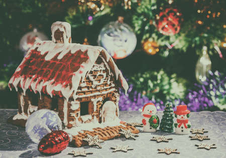 Christmas fairy house with a snowman and toys on the background of a festive Christmas tree. New Year card. Christmas still life. Fabulous village. Place for your text. Retro styleの写真素材