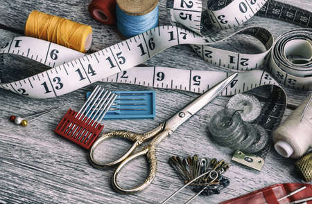 A set of sewing tools for sewing, spools of thread, fabrics, scissors and thimble close-up. Sewing threads for sewing and various accessories for needlework. retro styleの写真素材