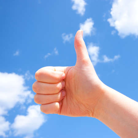 Thumb up over blue sky