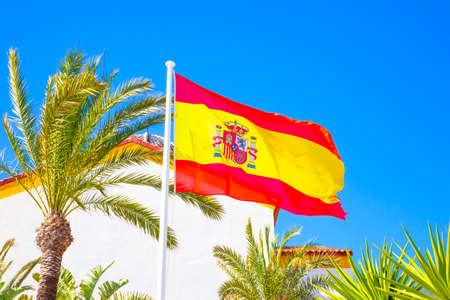 Spanish national flag over blue skyの写真素材