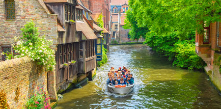 Bruges, Belgium - 17 May, 2022: Brugge old town, water canal and boat with touristsのeditorial素材