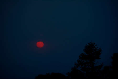 sun setting over the horizon at dusk with a dramatic sky of intense colorsの写真素材
