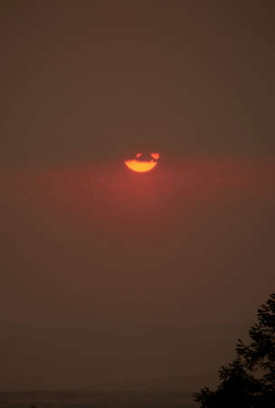 sun setting over the horizon at dusk with a dramatic sky of intense colorsの写真素材