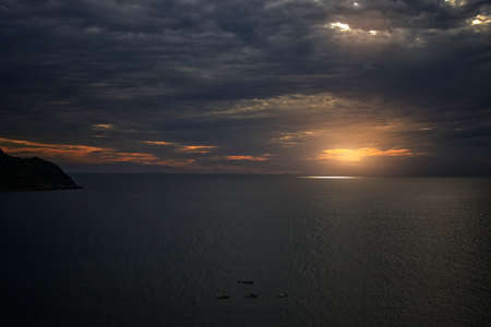 setting on the horizon at sunset with a dramatic sky of intense colors in the sea.の写真素材