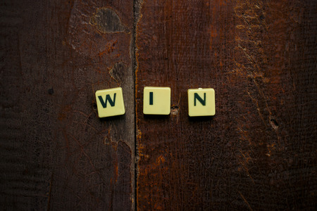 "win" word on wooden table done with a retro vintage filter and Len vignettingの写真素材