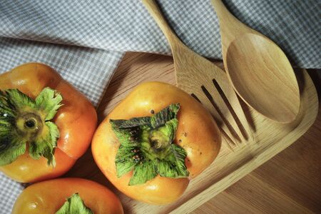 persimmons on wooden table focus on one pointの写真素材