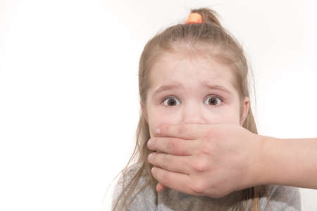 Scared little girl with an adult man's hand covering her mouth for any purposeの写真素材