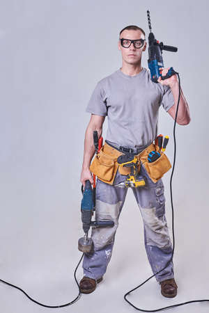 Master-Builder-finisher in their working clothes, with two drill machine in his hands for any purposeの写真素材