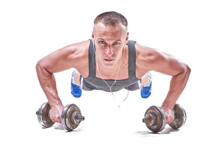Handsome sporty man wringing off the floor with dumbbells in his hands isolated on white background...