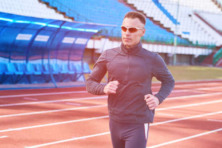 Handsome athletic man running on the treadmill stadium for any purposeの写真素材