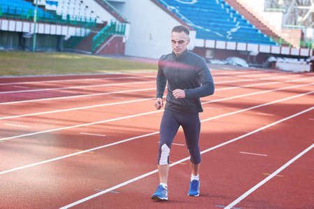 Handsome athletic man running on the treadmill stadium for any purposeの写真素材