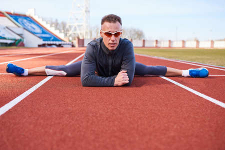 A man sportsman performs a transverse twine, on the athletics track of the stadium. For any purposeの写真素材