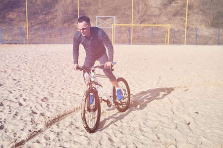 Cyclist with bike on the sand for any purpose