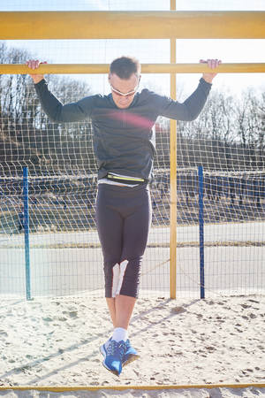 A handsome sports man pulls up on the gate for any purpose