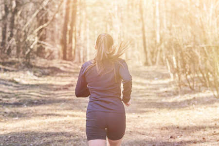 Sporty girl in the woods from the back, for any purposeの写真素材