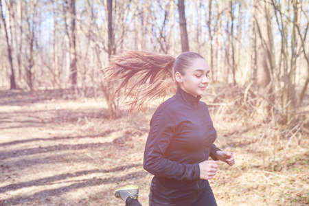 Sporty girl running in the woods for any purposeの写真素材