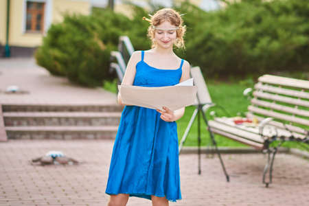 Beautiful girl-artist on the street in a blue dress draws a sketch of the picture for any purposeの写真素材