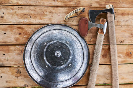 Shield and axe on wooden table for any purposeの写真素材