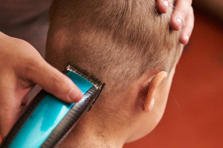 A man cuts machine child at home. For any purpose.