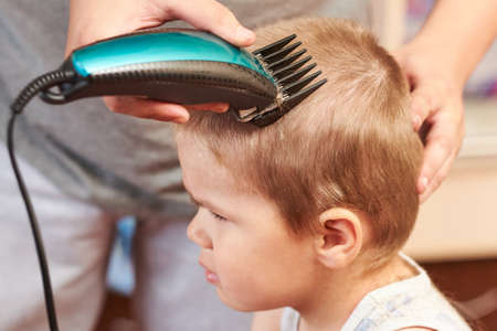 A man cuts machine child at home. For any purpose.の写真素材