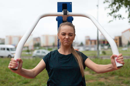 Beautiful athletic girl, trains arms and chest, on a street simulator. For any purpose