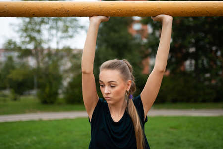Athletic blonde girl holds hands on the crossbar of a football goal. For any purposeの写真素材
