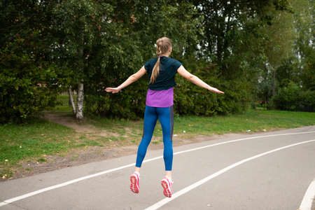 Athletic girl doing stretching on a street treadmill. For any purpose