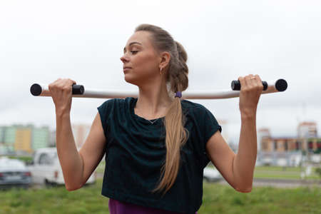 Beautiful athletic girl pulling herself up on a street trainer. For any purpose