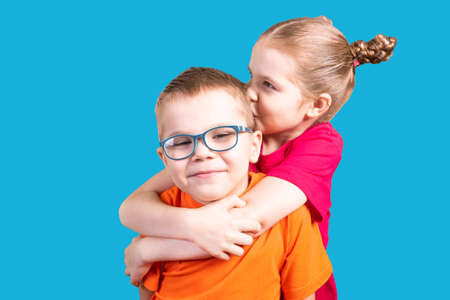 Brother and sister hugging and smiling. Isolated on a blue background. For any purpose.の写真素材