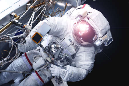 Astronaut in a spacesuit, with a reflection of the sun in a helmet. Elements of this image were...