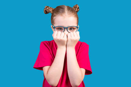 The girl bites her nails and got scared. Isolated on a white background.