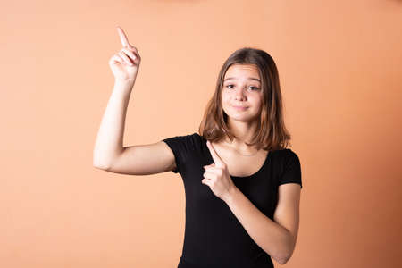 The girl points a finger upwards, on a light orange background. For any purpose.の写真素材