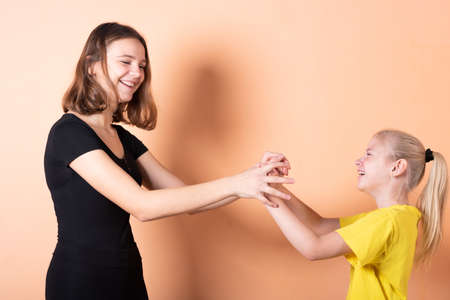 Sister asks her sister for a smartphone. on a light orange background.For any purpose.