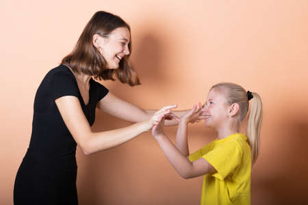 Sisters are playing, on a light orange background. For any purpose.の写真素材